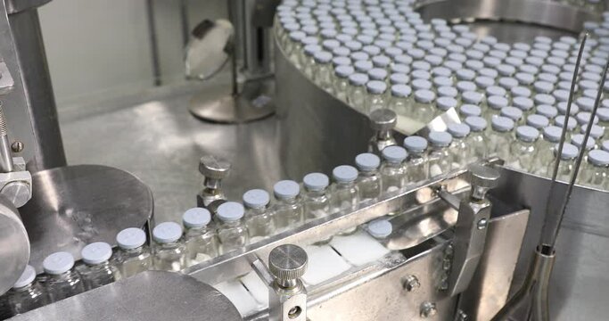 liquid vaccine injection manufacturing line glass vial bottle on a conveyor belt in a Pharma production factory  injections in small ampoule vials factory with latest hi tech machinery