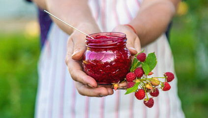 Raspberry jam in the hands of a woman. Selective focus.