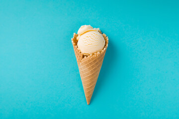 Vanilla ice cream in waffle cone isolated on blue background.