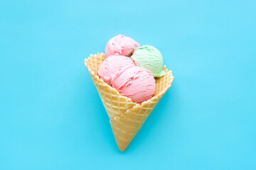 Colorful ice cream scoops in waffle cone on blue background
