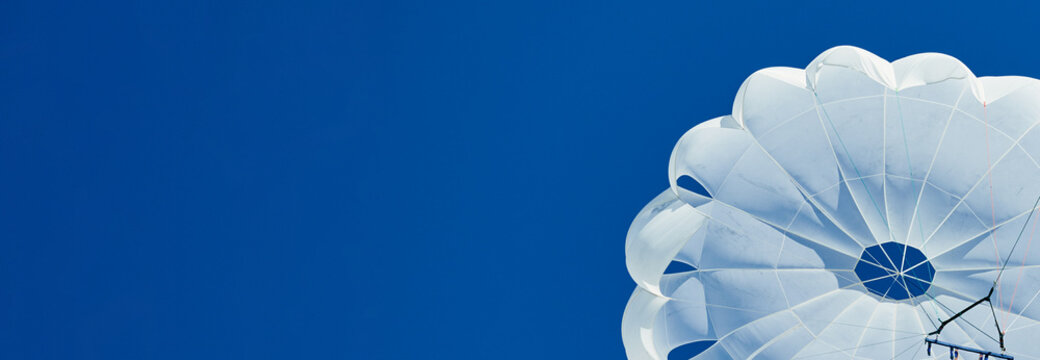 White parachute against a blue sky banner.