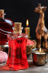 A bottle of red bath oil. There are many other spa cosmetics around it.