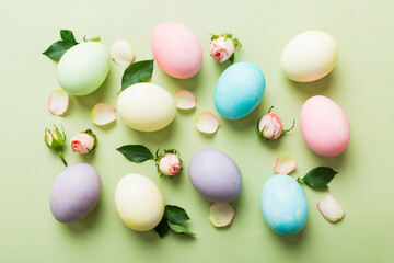 Happy Easter. Easter eggs on colored table with yellow roses. Natural dyed colorful eggs background top view with copy space