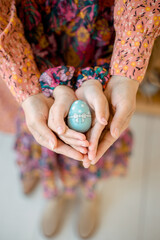 Hands of mother and daughter holding Easter egg