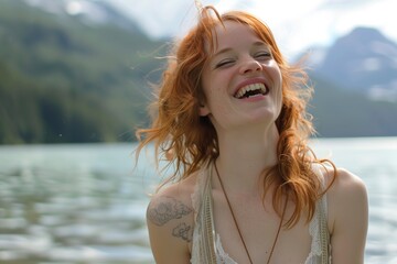 A woman with red hair smiles while standing by a body of water.