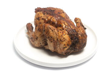 A whole delicious roasted chicken seasoned with herbs in a white plate isolated on white background clipping path