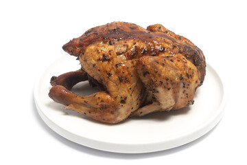 A whole delicious roasted chicken seasoned with herbs in a white plate isolated on white background clipping path