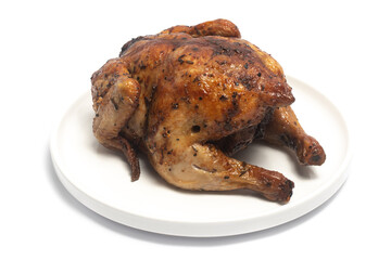 A whole delicious roasted chicken seasoned with herbs in a white plate isolated on white background clipping path