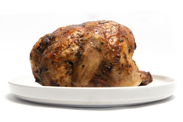 A whole delicious roasted chicken seasoned with herbs in a white plate isolated on white background clipping path