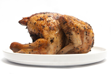A whole delicious roasted chicken seasoned with herbs in a white plate isolated on white background clipping path