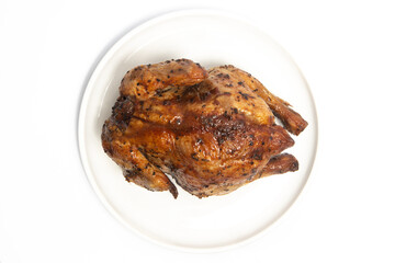A whole delicious roasted chicken seasoned with herbs in a white plate top view isolated on white background clipping path