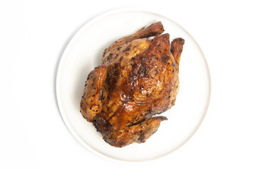 A whole delicious roasted chicken seasoned with herbs in a white plate top view isolated on white background clipping path