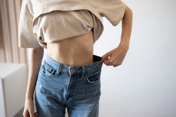 Woman Demonstrating Weight Loss by Pulling Away Large Jeans From Her Waist