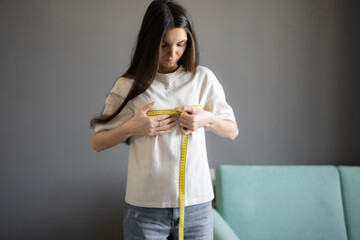 Young Woman in t-shirt Measuring Her Bust Size at home