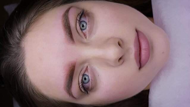 A young female model looks at the camera after a permanent eyebrow makeup procedure. Permanent makeup procedure, performing PMU of eyebrows