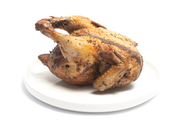 A whole delicious roasted chicken seasoned with herbs in a white plate isolated on white background clipping path