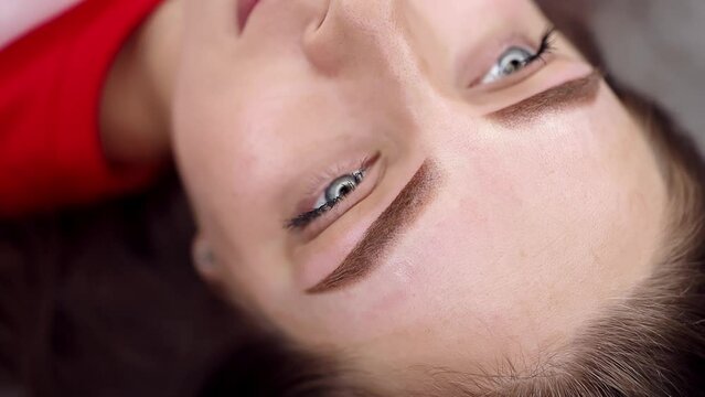 The completed work of permanent eyebrow makeup, the girl poses in front of the camera. Permanent makeup procedure, performing PMU of eyebrows