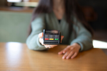 person Extending Arm holding bank terminal to Make a Contactless Payment transaction