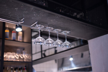 Upside Down Glassware Suspended Over a Bar Counter in Dim Lighting