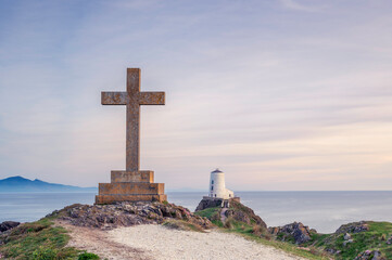 Ynys Llanddwyn Lighthouse and a religous cross, at sunset on a summers day. North Wales, Anglesey