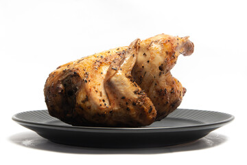 A whole delicious roasted chicken seasoned with herbs in a black plate isolated on white background clipping path