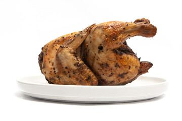 A whole delicious roasted chicken seasoned with herbs in a white plate isolated on white background clipping path