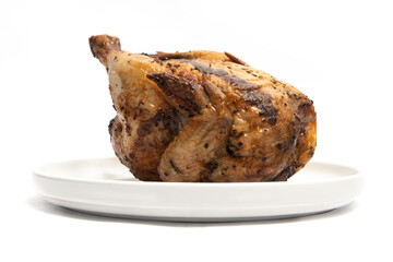 A whole delicious roasted chicken seasoned with herbs in a white plate isolated on white background clipping path
