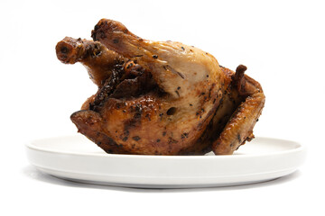 A whole delicious roasted chicken seasoned with herbs in a white plate isolated on white background clipping path