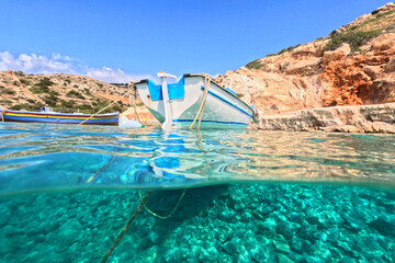 Underwater split photo of traditional fishing boat anchored in crystal clear sea of Mykonos island, Cyclades, Greece