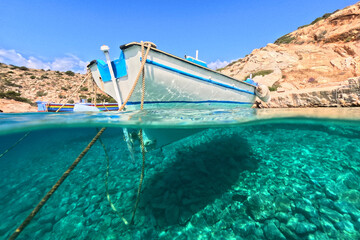 Underwater split photo of traditional wooden fishing boat anchored in turquoise sea of rocky bay in island of Crete, Greece - obrazy, fototapety, plakaty