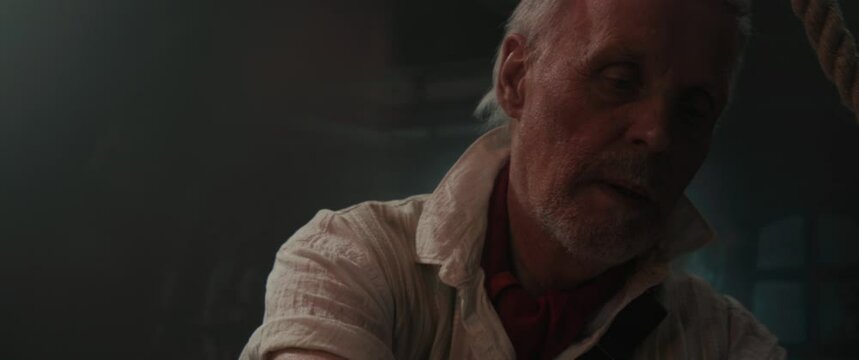An old pirate writes a letter sitting by the old table inside the sailing ship cabin