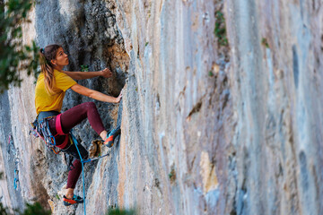 The girl climbs the rock. The climber trains on natural terrain. Extreme sport.  A woman overcomes a difficult route rock climbing..