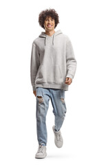 Fototapeta premium Full length portrait of a cute tall guy with curly hair in a gray hoodie and jeans walking towards camera