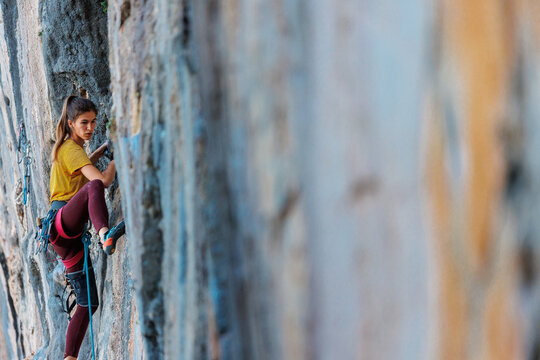 Climber overcomes challenging climbing route. A girl climbs a rock. Woman engaged in extreme sport. .