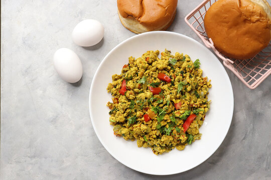 Anda Masala Bhurji or Spicy Indian scrambled eggs with bread or Bun Pav, a popular street food in Mumbai. Served in a white plate along with copy space. egg bhurji or parasi akuri. with jowar bhakri.