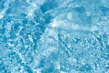 Blue water surface texture with ripples, splashes, and bubbles. Abstract summer banner background Water waves in sunlight with copy space cosmetic moisturizer micellar toner emulsion. Blue water wave.