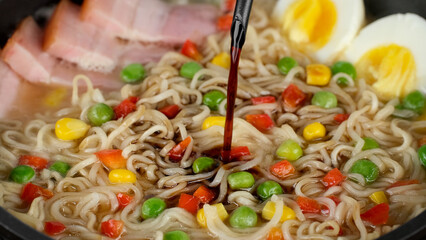 Cooking ramen noodles with eggs and bacon, close up