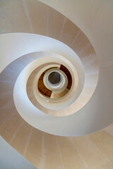 Birds eye view of a modern helix or circular staircase in white and beige colors with view from top to bottom