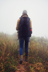 Person, hiking and back in countryside for trekking, sticks and support for fog trail in mountain....