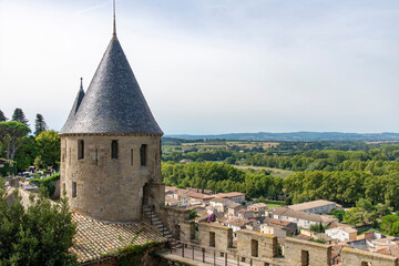 Fototapeta na wymiar View over fortified wall with battlement and tower towards French landscape of the city of Carcassonne, a medieval fortress from Gallo-Roman period and part of UNESCO list of World Heritage Sites