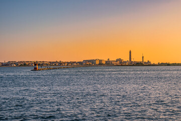 Fototapeta premium Breakwater of Aveiro estuary with buildings and Barra lighthouse in the horizon at golden hour, Gafanha da Nazaré PORTUGAL
