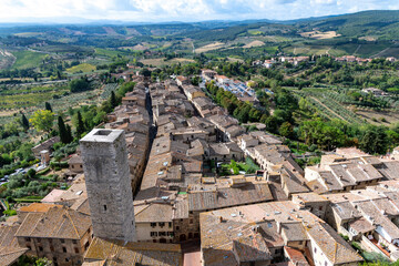 High angle panoramic view over San Gimignano, Italy with view on the tower Torre dei Cugnanesi  and typical Tuscan landscape in the background - obrazy, fototapety, plakaty