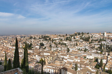 Fototapeta na wymiar High level panoramic view over the city of Granada, Spain seen from the Alhambra palace with on far-right Mirador de San Nicolás square known for dramatic sunset views and Sierra Nevada in background