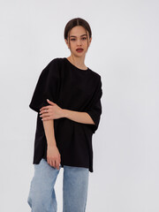 mockup of a black loose-fitting t-shirt on a young beautiful girl