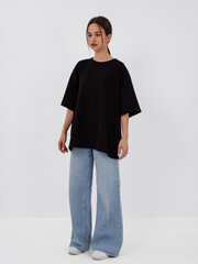 mockup of a black loose-fitting t-shirt on a young beautiful girl