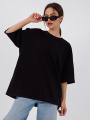 mockup of a black loose-fitting t-shirt on a young beautiful girl