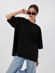 mockup of a black loose-fitting t-shirt on a young beautiful girl