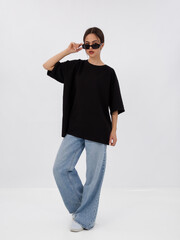 mockup of a black loose-fitting t-shirt on a young beautiful girl