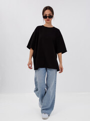 mockup of a black loose-fitting t-shirt on a young beautiful girl