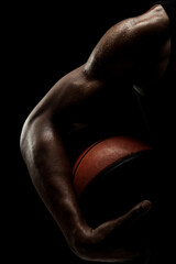 Basketball player holding a ball against black background. Abstract male body of african american...